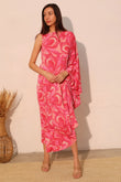 Woman wearing a pink patterned dress against a beige wall.