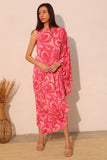 Woman wearing a pink patterned dress against a beige wall.
