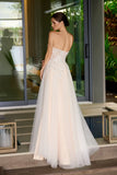 Woman in a nude strapless wedding gown standing in an outdoor setting with large windows and plants.
