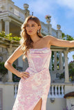 A woman with long wavy hair models the Juliet JT2737A, a strapless floral prom dress featuring a corset bodice and thigh-high slit, standing outdoors in front of a grand building with columns and balconies.