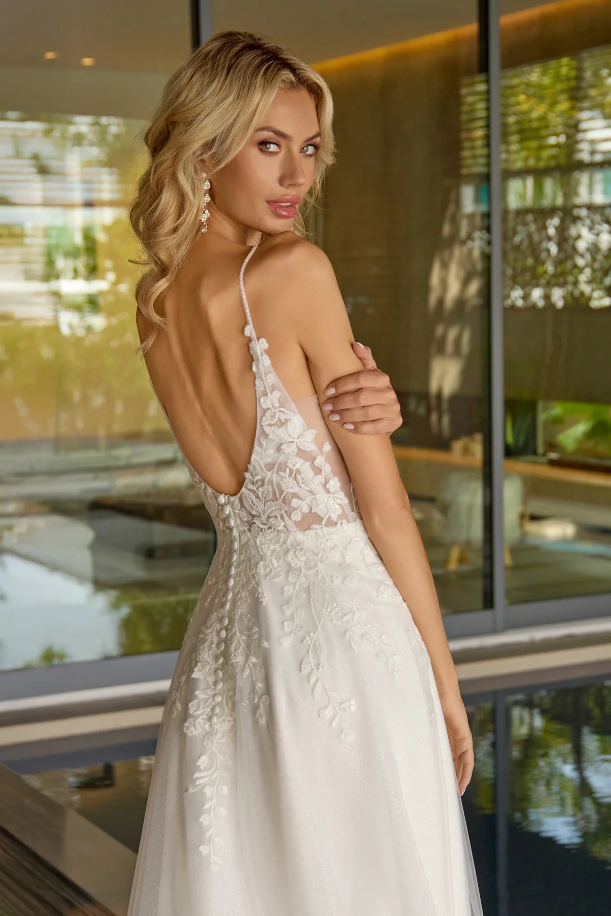 Woman in a white lace dress standing indoors with a blurred background