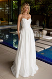 Woman in a strapless white wedding dress standing by a poolside.