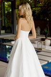 Woman in a white strapless gown standing by a poolside.