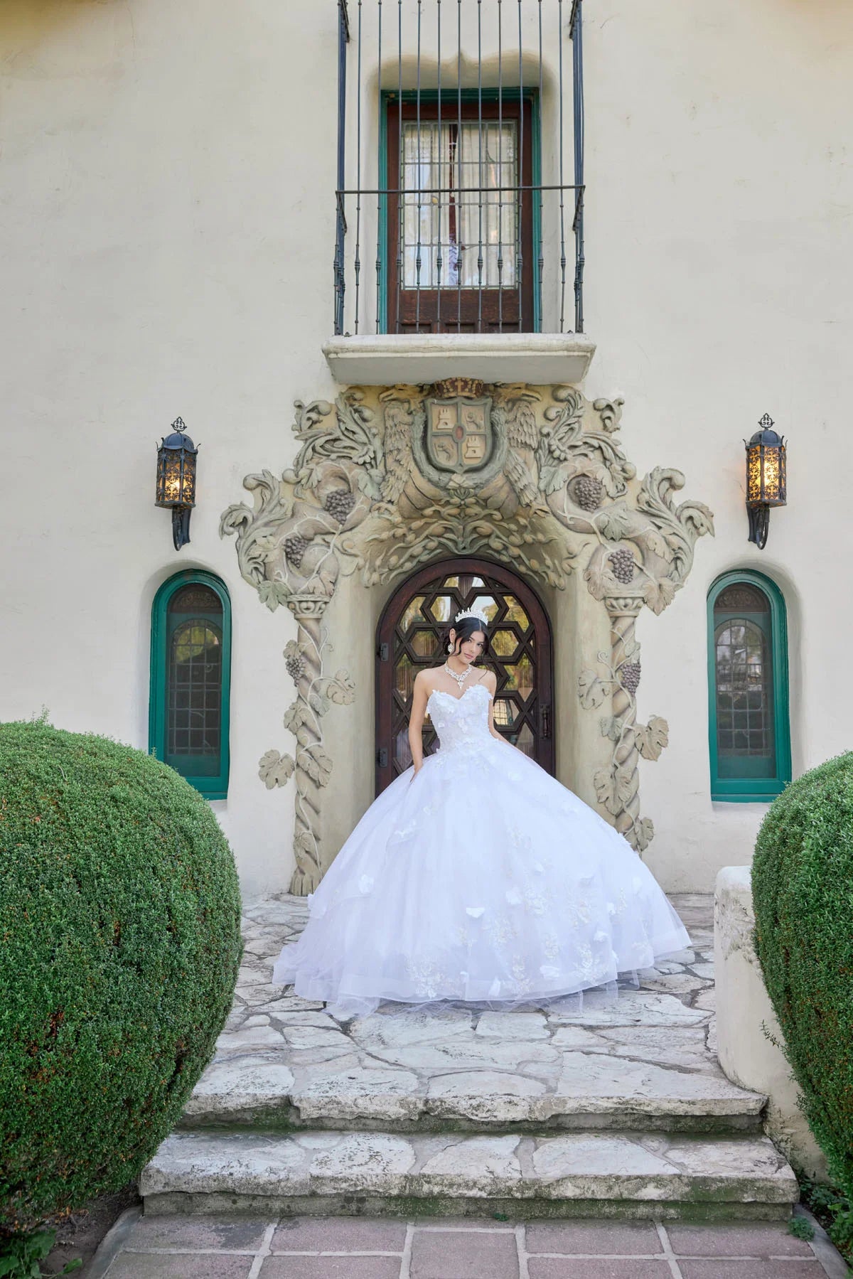 Woman in a white wedding dress standing in front of an ornate building entrance.