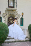 Woman in a white wedding dress standing in front of an ornate building entrance.