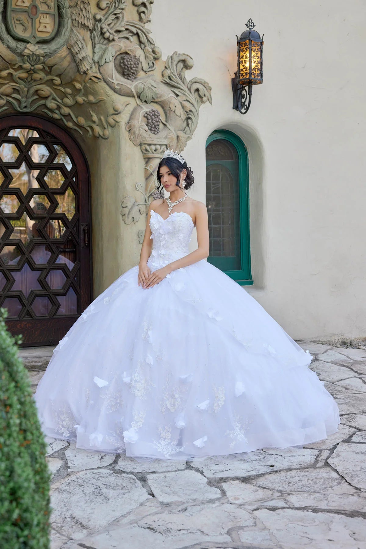 Woman in a white wedding dress standing in front of an ornate building entrance.