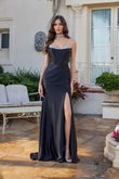 A woman poses outdoors in front of a white house, wearing the Juliet JT2698A long black prom dress with a strapless satin corset bodice, hot stone embellishments, high slit, and a matching choker necklace.