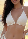 Woman wearing a white bikini on a beach with a blurred background