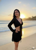 Woman in a black outfit standing on a beach at sunset