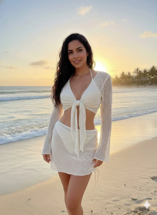 Woman in a white outfit standing on a beach with sunset in the background
