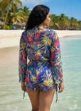 Woman in a colorful floral outfit standing on a beach with palm trees in the background